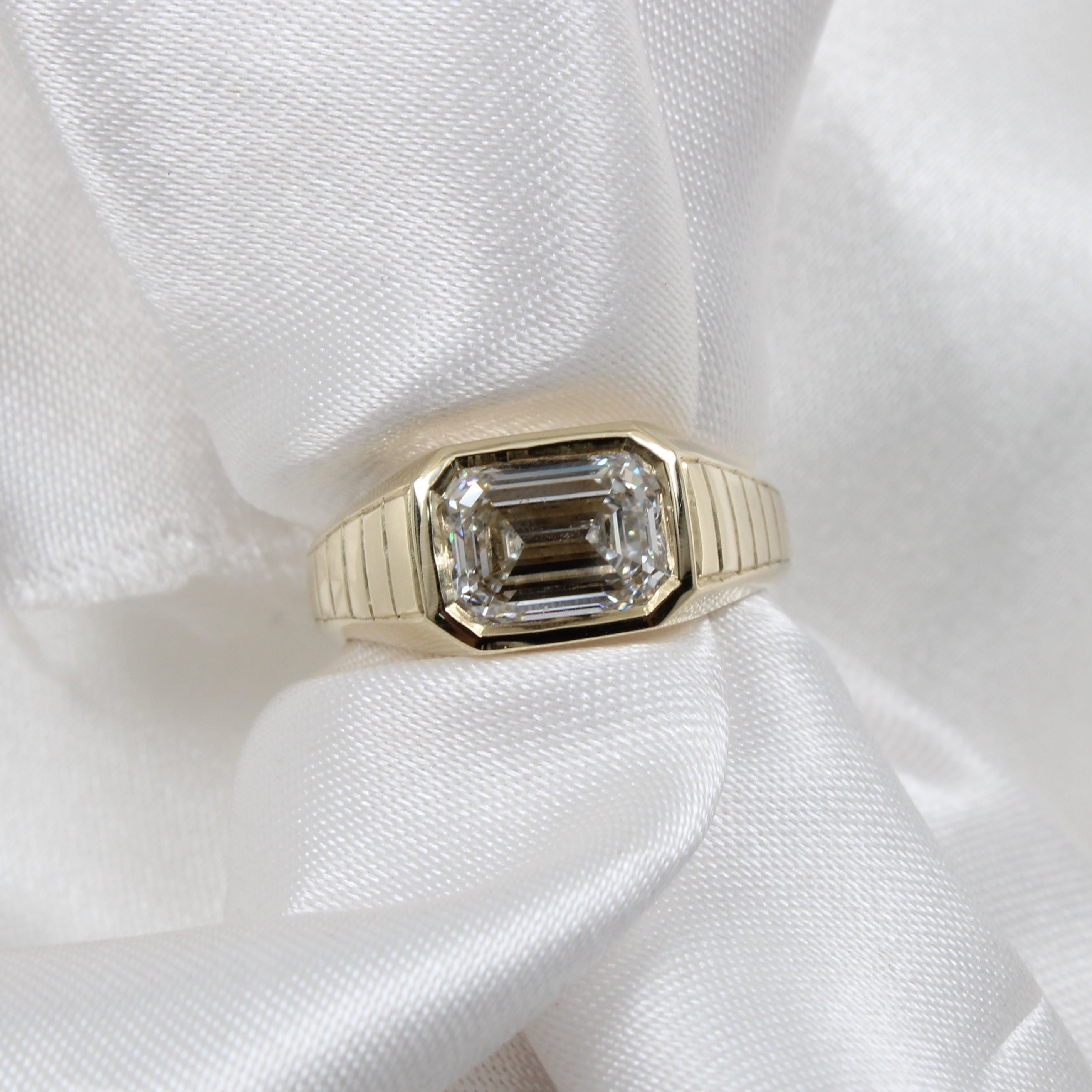 Vintage inspired chunk gold ring with a diamond and engraving on a white fabric background