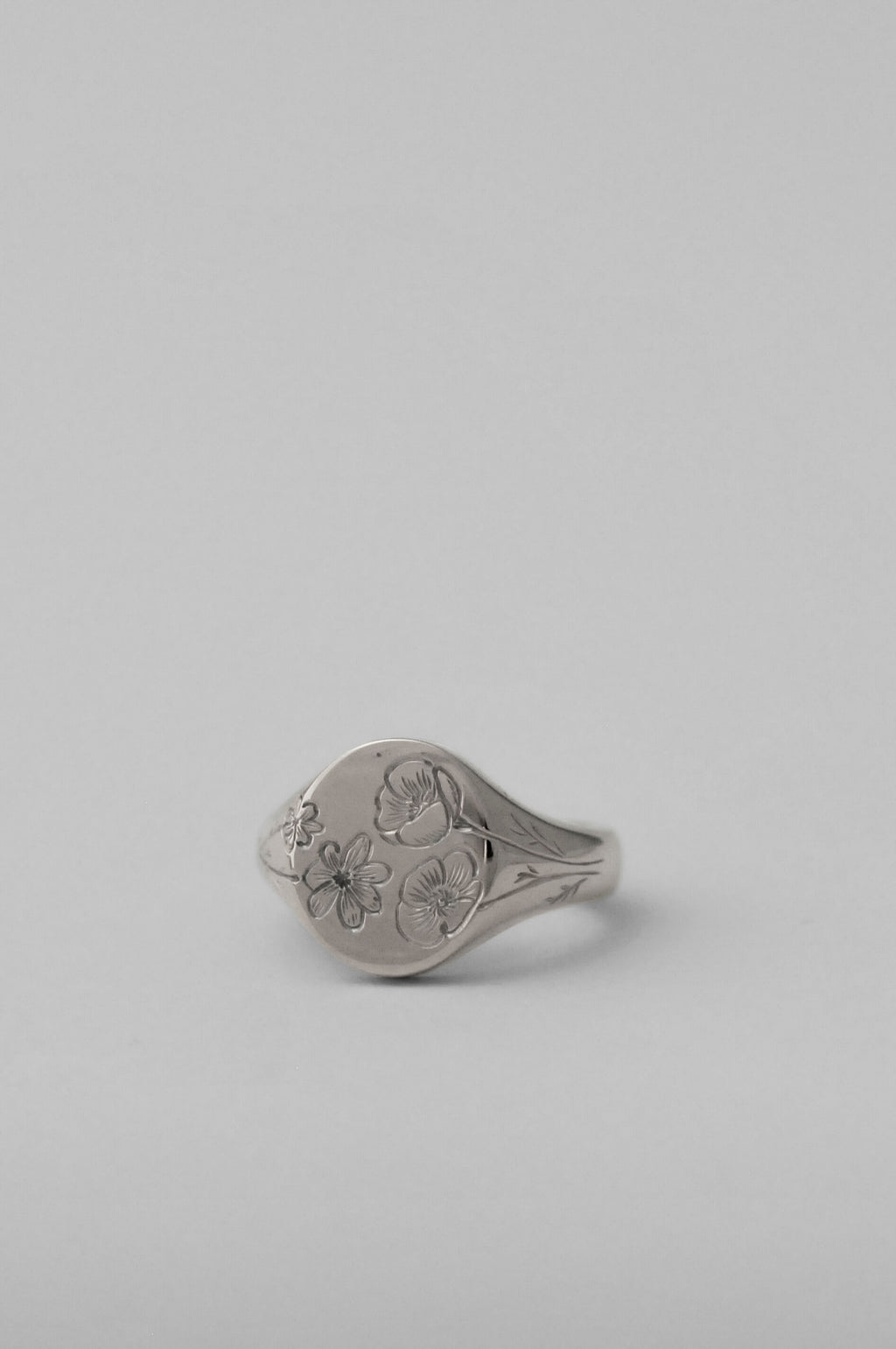 A timeless silver pinky signet ring with personalised floral birth flower engraved design, shown on a neutral light grey background.