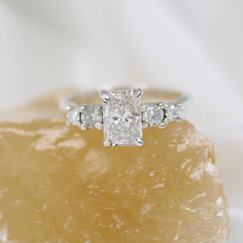 Emerald cut Diamond ring on a rough diamond block with a white background