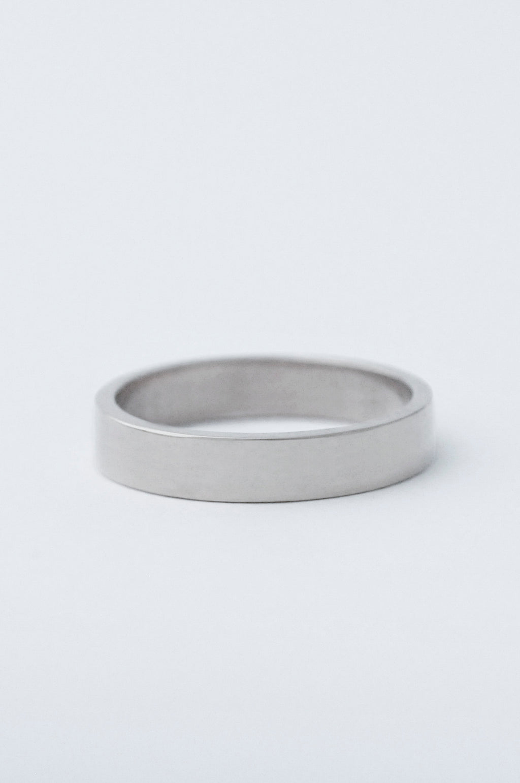A chunky platinum wedding band, resting on a clean white surface.