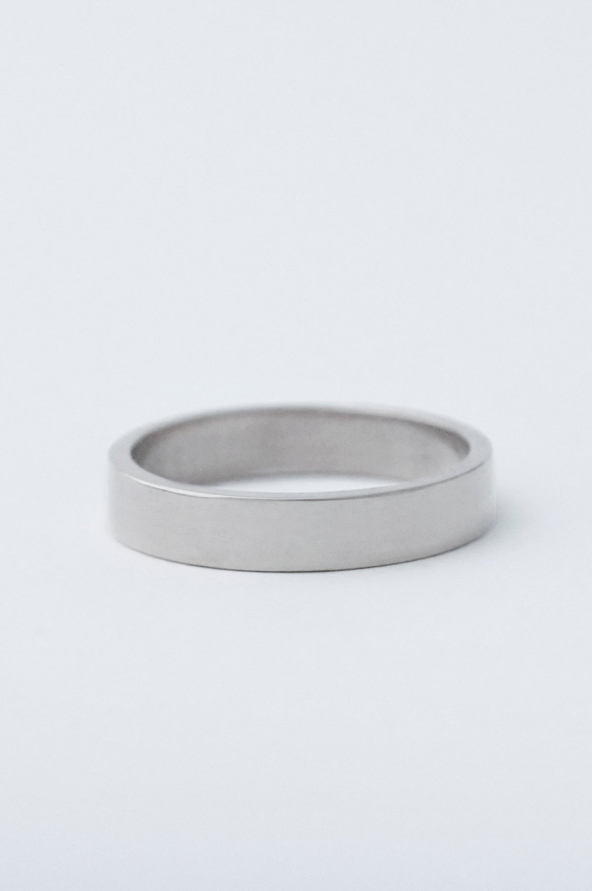 A chunky platinum wedding band, resting on a clean white surface.
