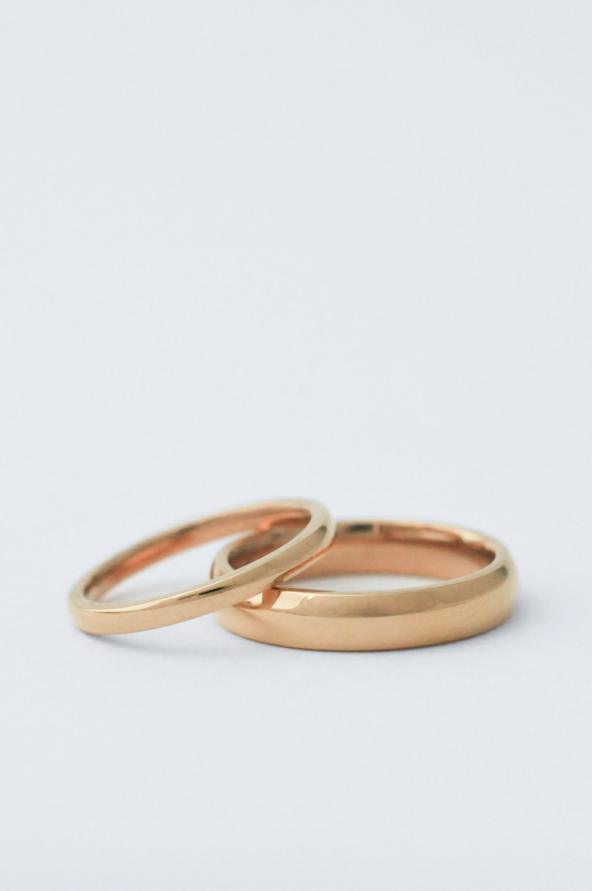 two court wedding bands staggered on top of each other. The bottom ring is 5mm thick and the top one is 2mm both in yellow gold