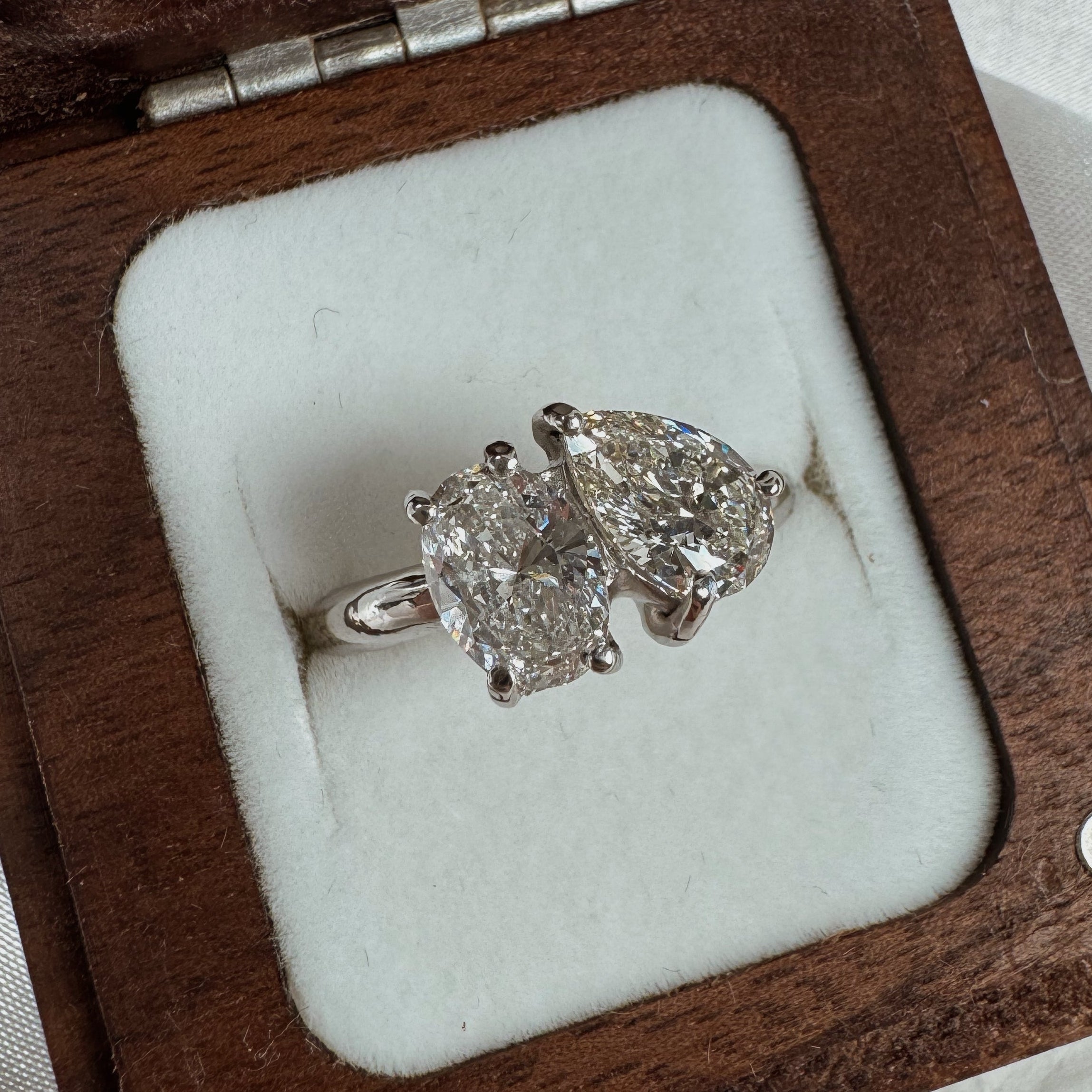 Diamond toi et moi engagement ring in a wooden box on a white fabric background